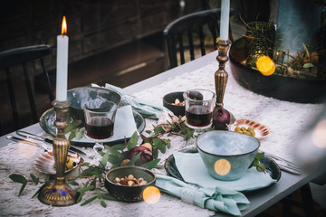 Decorated greenhouse in trendy christmas setting with dinner table, candles and christmas lights.