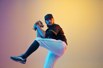 Baseball player, pitcher in a black uniform practicing and training on gradient background in neon...