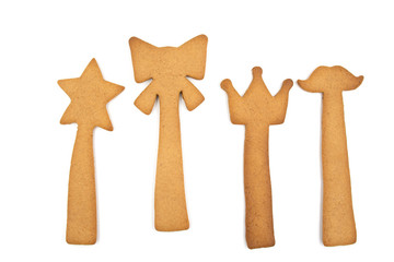 Homemade gingerbread cookies: star, bow, crown and moustache on a stick isolated on a white background.
