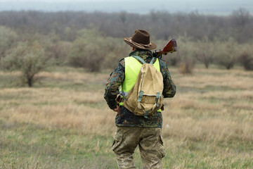 Hunting period, autumn season open. A hunter with a gun in his hands in hunting clothes in the...