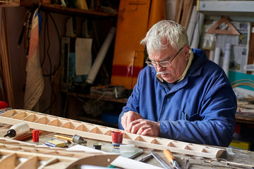 Senior man who makes the wing of a radio-controlled aircraft, the construction of the airplane.