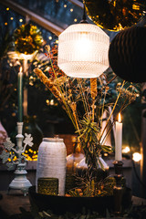 Decorated greenhouse in trendy christmas setting with dinner table, candles and christmas lights.