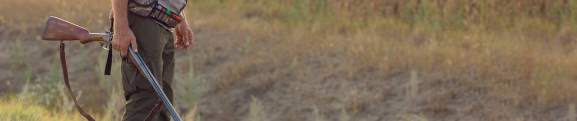 Hunter with a hat and a gun in search of prey in the steppe, Aims for prey. Panoramic image for...