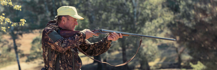 Hunter with a hat and a gun in search of prey in the steppe, Aims for prey. Panoramic image for...