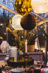 Decorated greenhouse in trendy christmas setting with dinner table, candles and christmas lights.