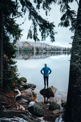 Fototapeten Young man standing alone an staring at lake. Foggy air. Early chilly morning in winter. © kovop58