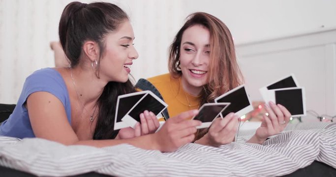 Girlfriends looking at old photos on bed