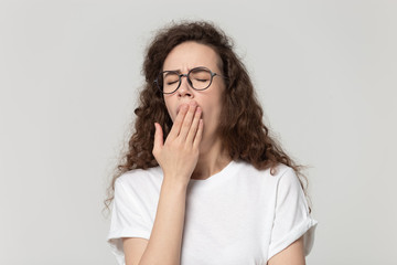 Exhausted millennial girl in glasses yawn covering mouth