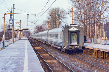 Naklejka na ściany i meble Passenger train departs from the platform at autumn morning time..