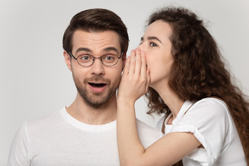 Millennial girl whisper secret in amazed boyfriend ear