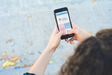 Women's hands holding smartphone showing statistics about company growth