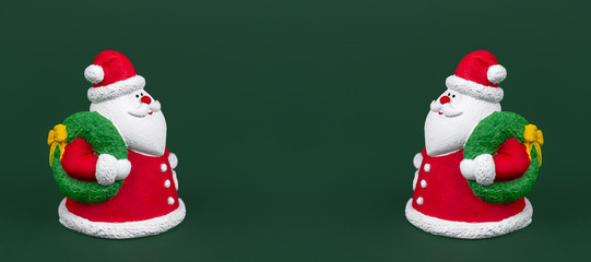 Two happy gypsum colorful santa claus isolated over green background. New Year and Christmas concept. Copy space