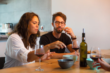 Positive couple enjoying snacks and wine with friends. Young man and woman in casual meeting indoors. Communication concept