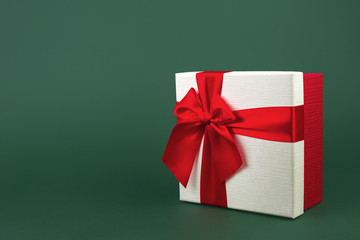 Cute minimalist christmas gift box with ribbon isolated over green background.