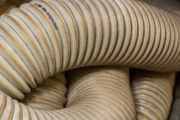 collection of Beige and white brown crinkled tube for air conditioning or feeding other things from one side of a factory to another side in the industrial working environment but stacked together