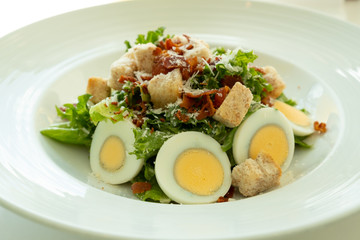 Egg salad topping with mozzarella cheese and crispy chopped bacon in white plate. Closed up shot