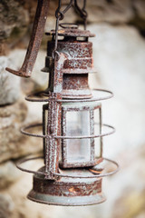 old rusty kerosene lamp hanging on stone background