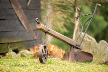 old iron plow with steel wheel placed as garden decoration