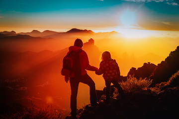 mother with little daughter enjoy travel in sunset mountains