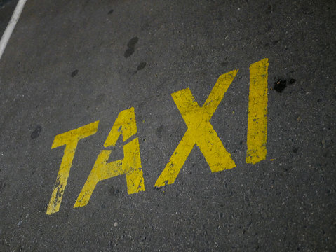 Yellow taxi inscription on the pavement. A place for parking and waiting for a taxi driver.