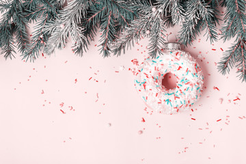 Christmas creative background with Christmas bauble made of glazed donut and sugar sprinkling