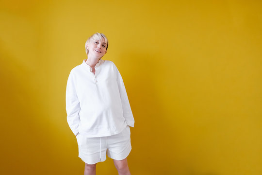 Close-up of a positive beautiful young pregnant woman posing in studio on yellow background. Smiling Caucasian woman rejoices at the long-awaited first-born. Pregnant Woman Health Concept