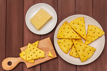 Cheese crackers, salty snack concept. Cookies, piece of cheese, cutting board. Wooden planks background