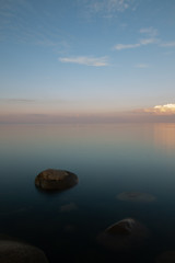Fototapeta na wymiar Rocks resting in the shallow and peaceful sea during evening hours