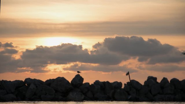 Time lapse of a sea sunset in Thessaloniki, Greece. Some birds and boats cross the frame. Cloudy sky. Fixed shot.