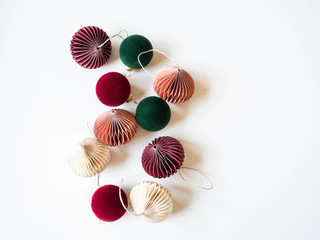 Multicolored paper origami Christmas decorations and Red and green velvet Christmas balls on white background. Copy space. Top view