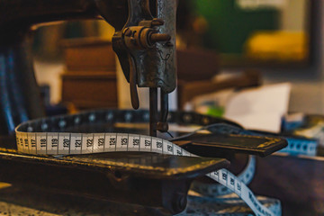Measuring tape and old sewing machine on tailor table.