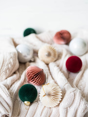Creative cozy Christmas composition with fir tree and different Christmas balls on white knitting background.