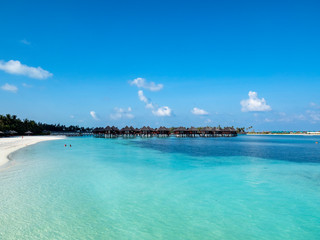 Fototapeta na wymiar Maldives island with beach water bungalows and palm trees, South Male Atoll, Maldives