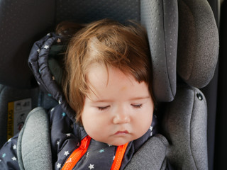 The child sleeps in a child car seat. child safety in the car. Sleeping baby while traveling.