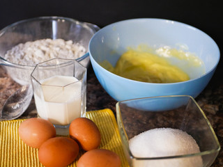 Ingredients for baking dough. flour, eggs, milk. Baking ingredients. Spoon on a marble table. Preparation for cooking.