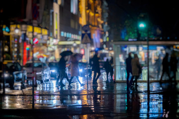 crowd of people walking on the city streets  on rainy night 