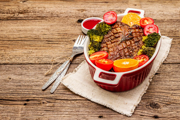 Baked duck breast on the bone with vegetables and sauce. Traditional healthy food concept. Vintage wooden boards background