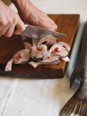 hands of a fisherman carve river fish on the table