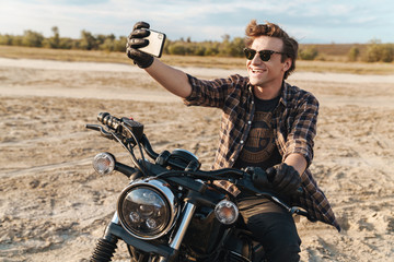 Fototapeta premium Man biker outdoors at the desert field take a selfie