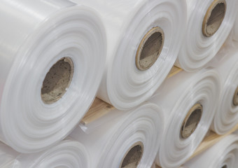 Close up montage of white transparent plastic roll in stacks of stock in a factory for commercial use wrapped in rolls over cardboard heavy duty tubes stacked high background texture