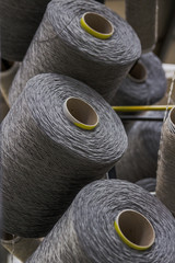 Large collection of thread and yarn in rolls stacked high on a metal grid ready to be fed down to a machine to weave them all together an industrial commercial factory create textiles materials rugs