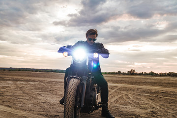 Fototapeta na wymiar Young man biker on bike outdoors at the desert field.