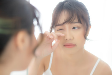 Beautiful and makeup young asian woman looking mirror aging on face and touch eye, beauty asia girl of skincare cosmetic for anti acne wrinkle, healthy care and wellness concept.