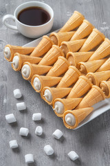 Cookies cone, coffee and marshmallows on a wooden gray table..