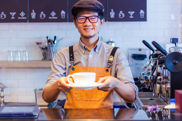 small business owner standing with coffee machine in his own coffee shop holding cup of coffee