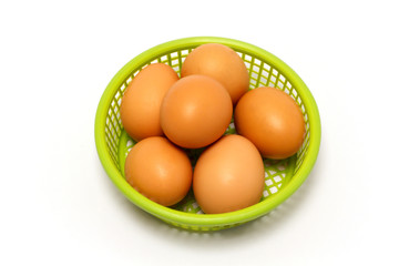 Chicken eggs are placed in a green basket.