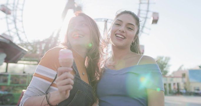 Girlfriends eating candy at amusement park