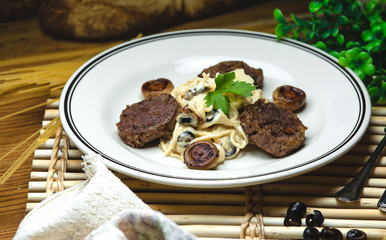 spaghetti in a creamy sauce with fried mushrooms and meat cutlets