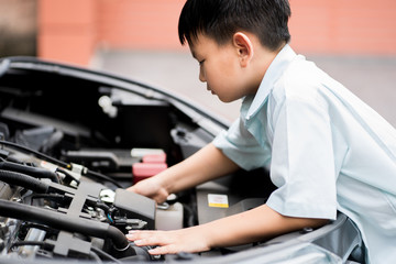 Mechanic boy working and repair car engine in car service centre.Automobile metal car engine part details.Concept of modern vehicle motor,Industry,Mechanic and Business.