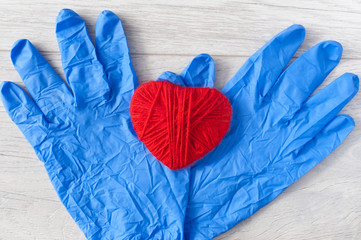 blue gloves and red heart  on white wood background.